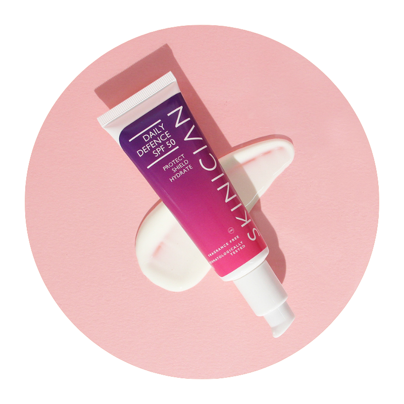 Image of Skinician Daily Defence SPF 50 tube laying on a swipe of the cream texture on a pink background