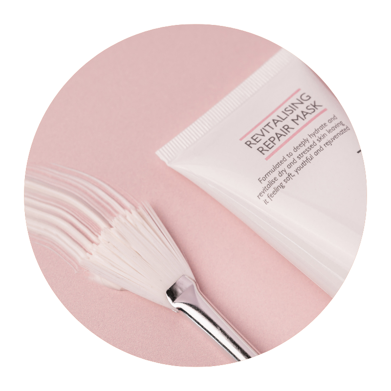 Round image of Skinician Revitalising Repair Mask next to a mask brush on a pink background