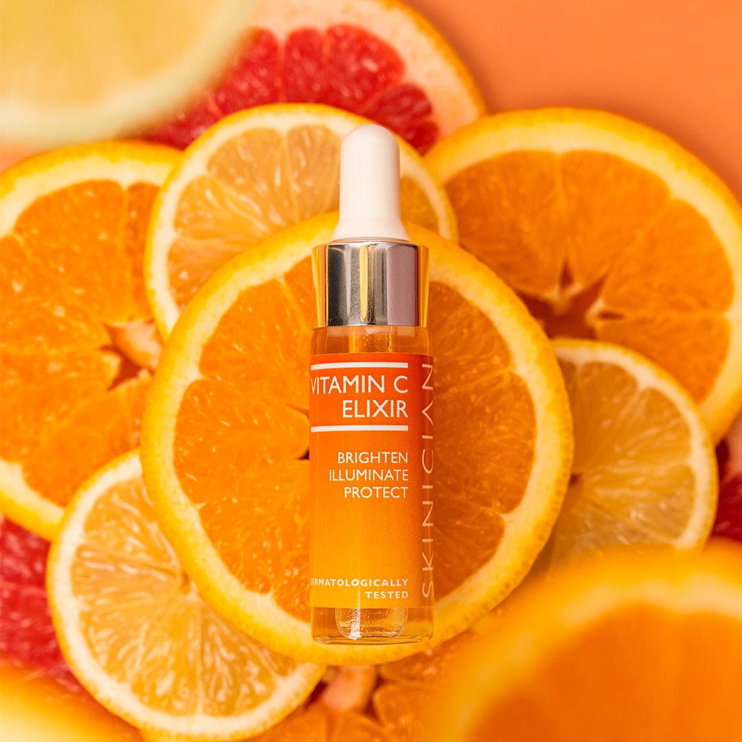 SKINICIAN Vitamin C serum for the face shown in a glass bottle on top of oranges.  Label reads 'Brighten' 'Illuminate' 'Protect'.  Dermatologically tested.