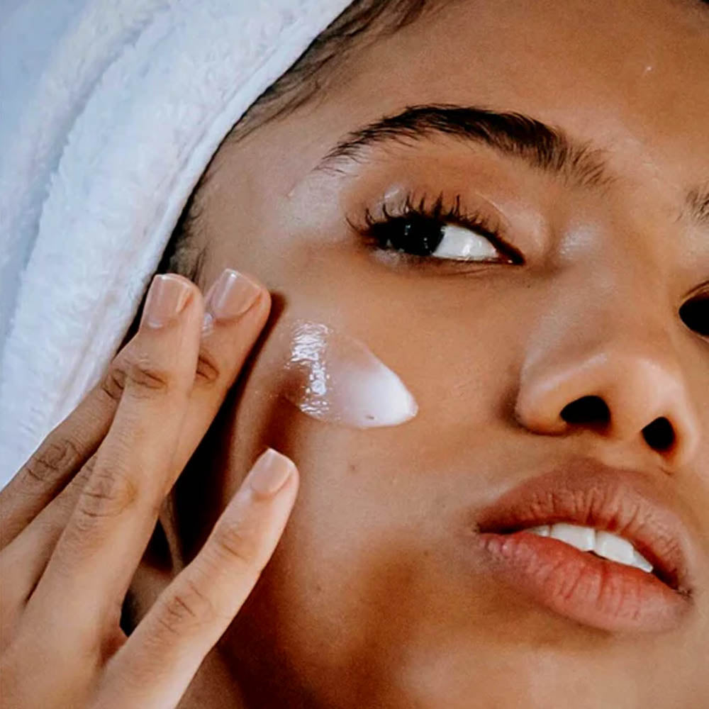 Woman applying cream to her cheek