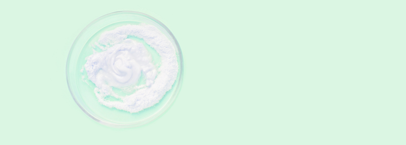 Image of white powder in a glass bowl on a green background to represent Zinc PCA