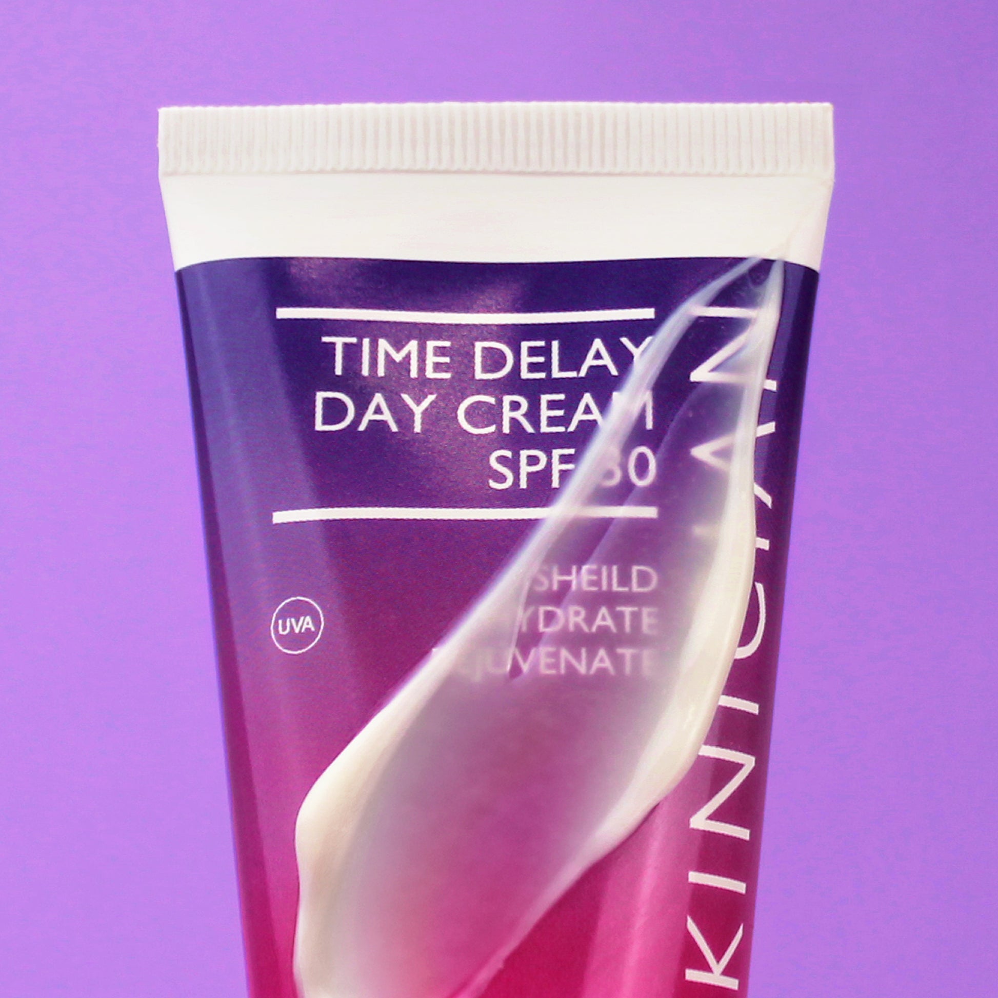 Tube of Skinician Time Delay Day Cream SPF 30 on a purple background with the cream product smeared on the bottle to show the texture