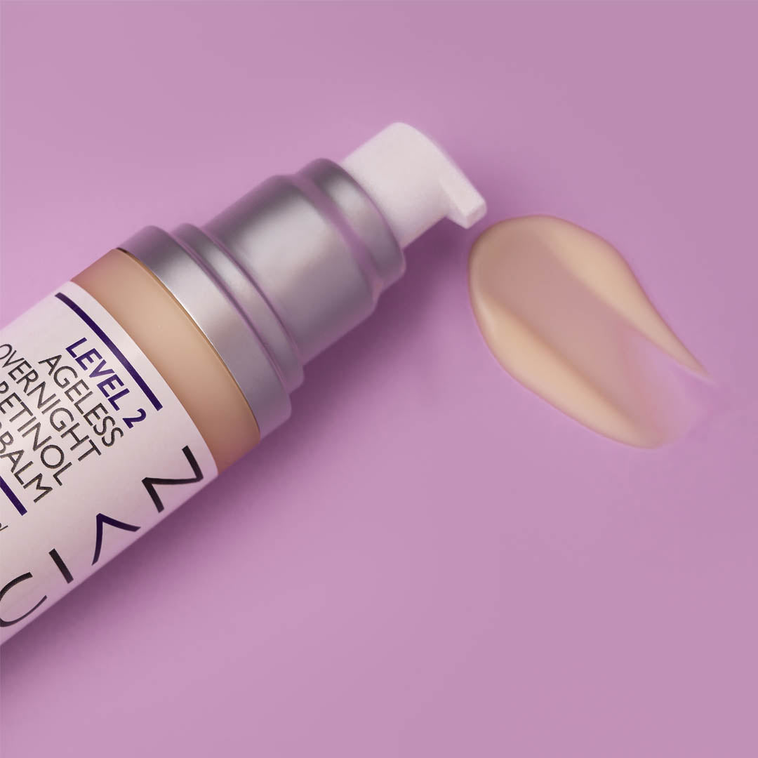 Ageless Retinol Night Cream bottle lying on its side with the texture of the retinol cream beside the bottle