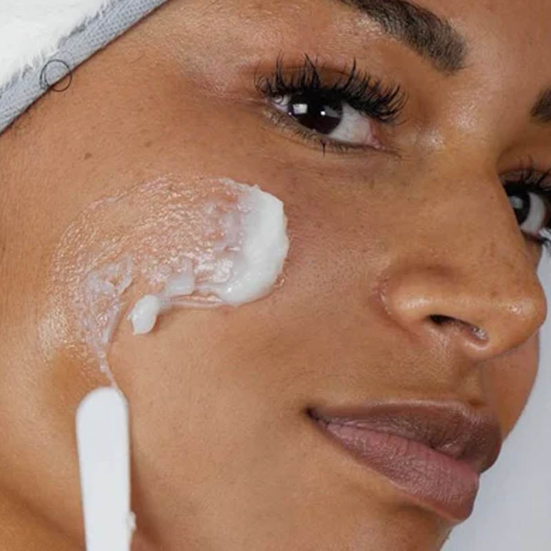 Image of woman applying cleansing balm to her cheek using a spatula
