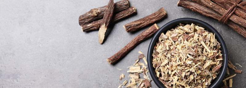 Image of liquorice sticks in its natural form beside a bowl of liquorice shavings