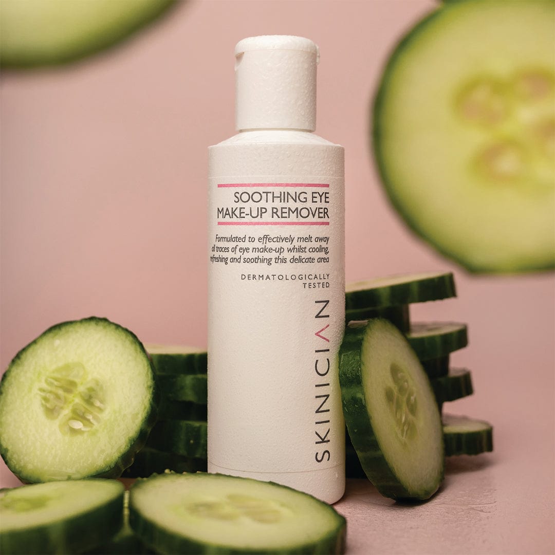 Eye make up remover bottle with cucumber around the bottle on a pink background