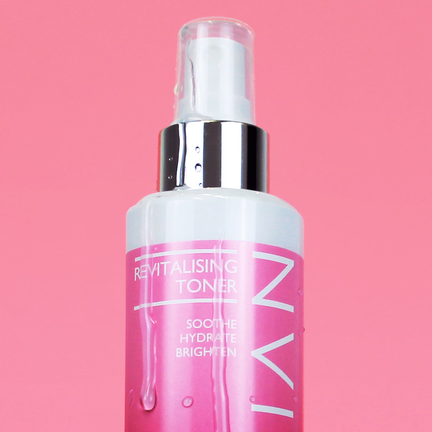 Close up image of Skinician Revitalising Toner on a pink background. The image shows the liquid product running down the side of the bottle