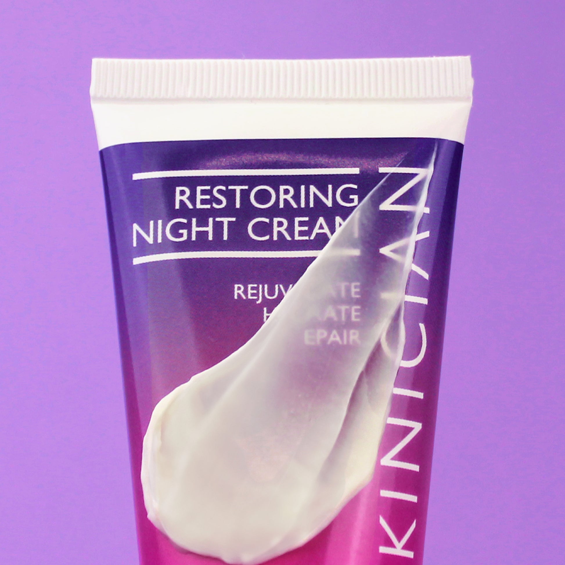 Skinician restoring night cream tube on a purple background with the product swatched on the tube to show the creamy texture