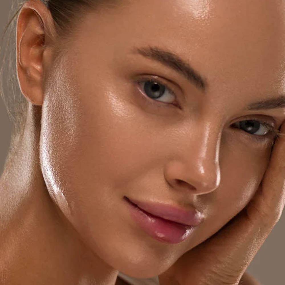 Image of young woman holding her hand face in her hand. The woman's skin is shiny and suggests she has oily skin