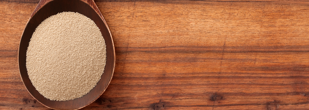 Image of a wooden bowl containing yeast extract - a fine, beige coloured powder-like substance