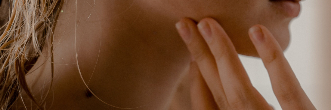 Close of woman's jaw area with her hand pressing against her cheek.