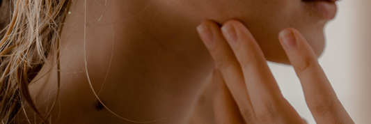 Close of woman's jaw area with her hand pressing against her cheek.