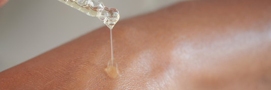 Close up of a woman's arm with a pipette of hyaluronic acid pouring serum onto the skin