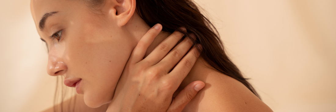 Close up image of a woman tilting her head and her hand cupped under her jaw, pressing on her neck