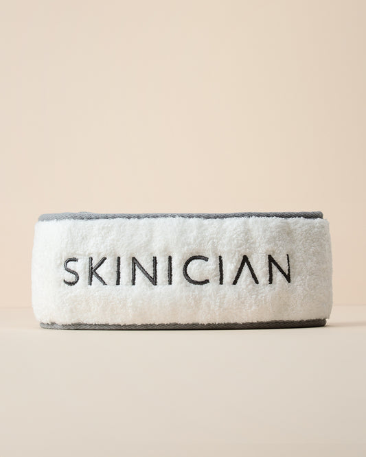 Gray and white headband with 'Skinician' branding on a beige background