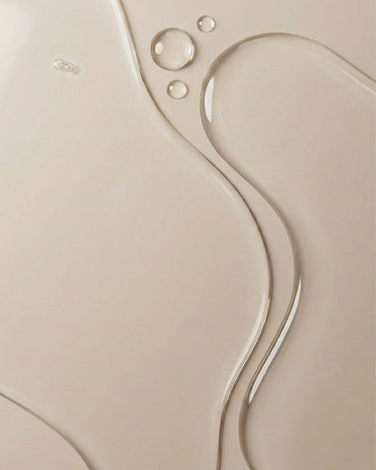 Close up image showing the liquid texture of Glycolic Exfoliating Toner on beige surface