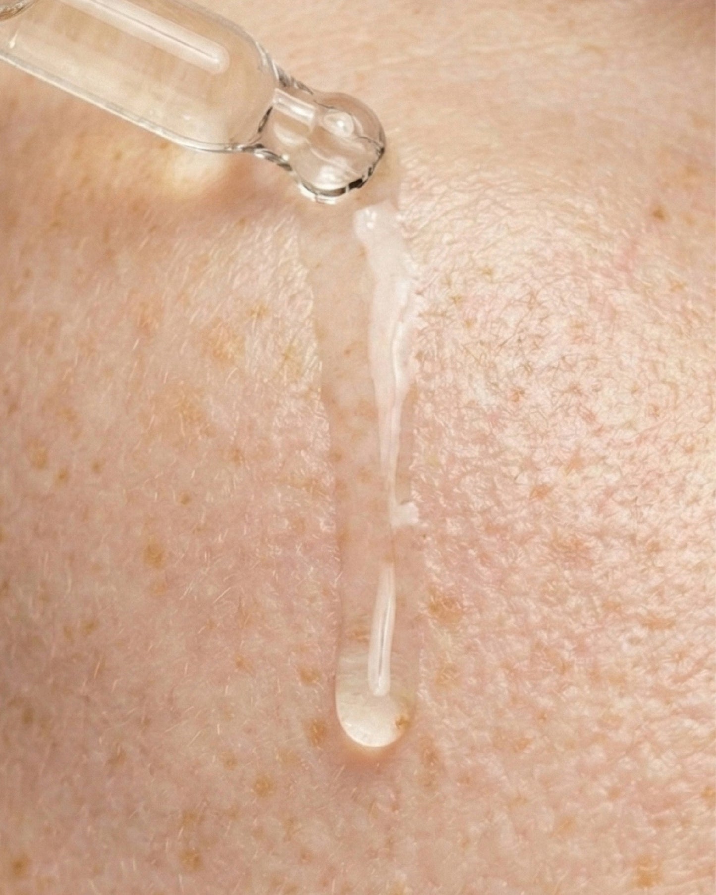 Pipette dripping Vitamin C Elixir onto skin to show oil texture