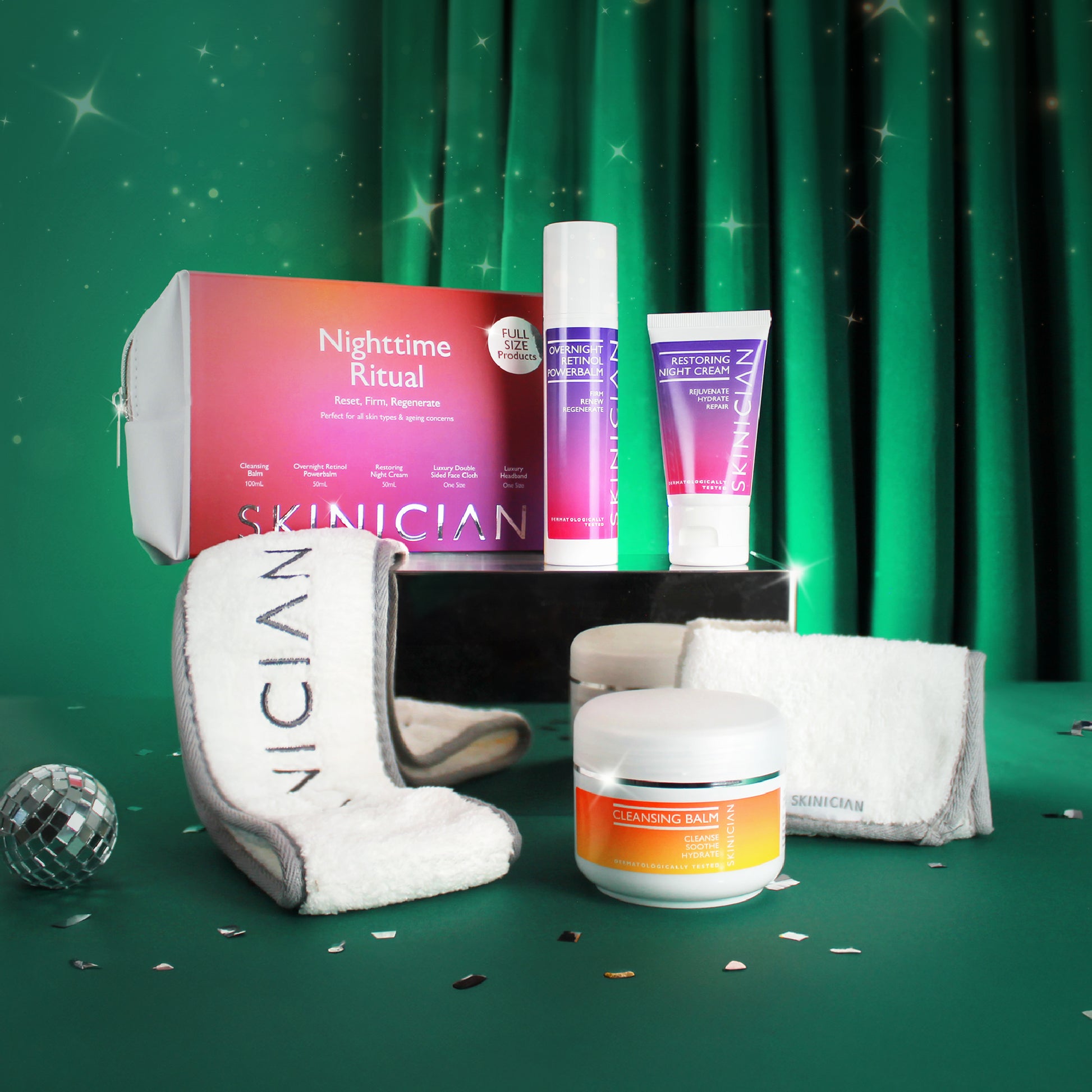 Skinician Nighttime Ritual gift set to Reset, Firm, Regenerate skin, all products set out on display on a Green velvet Christmas back ground with sparkles