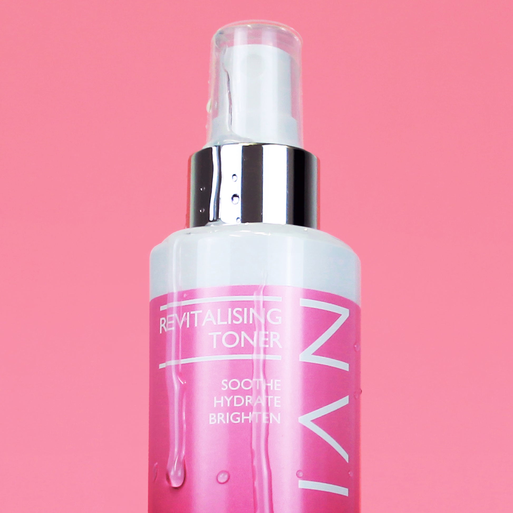 Close up image of Skinician Revitalising Toner on a pink background. The image shows the liquid product running down the side of the bottle